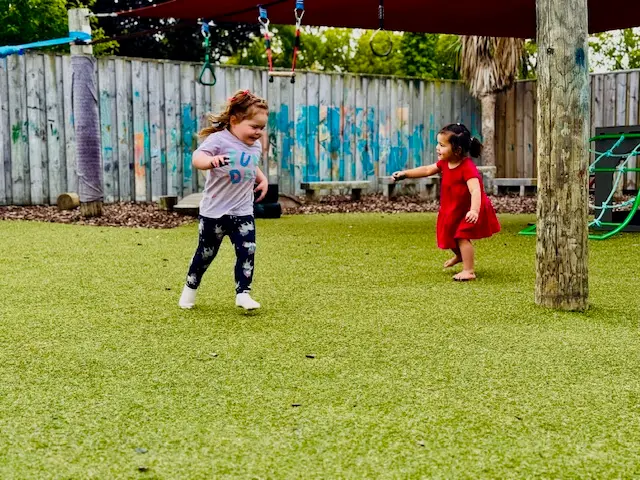 Child smiling while playing in the sand at Ōtipua Grove